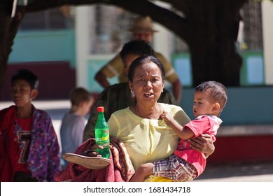 Bago, Myanmar - December 22, 2011: A Burmese Woman Holding A Child And A Bottle With Soft Drink