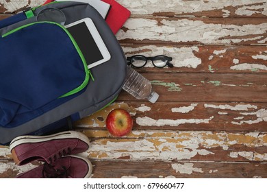 Bagpack, water bottle, apple, digital tablet, shoes and spectacle on wooden background - Powered by Shutterstock