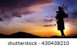 Bagpipe player in silhouette against dramatic sunset sky