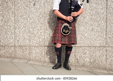 Bagpiper Dressed In Kilt Playing Bag Pipes