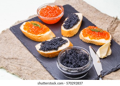 Baguette with red and black caviar on linen napkin on white table