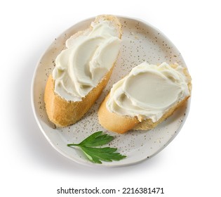 baguette slices with cream cheese on plate isolated on white background, top view