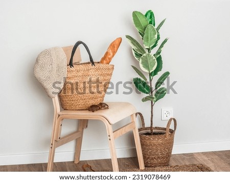 Baguette in a straw bag , hat on a wooden chair in the hallway
