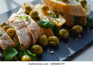 Baguette stuffed with olives, cut with fresh green olives and parsley, served on a stone plate, healthy appetizer - Powered by Shutterstock