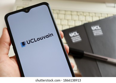 Bahia, Brazil - December 2, 2020. Person Holding Smartphone With UCLouvain Logo On Screen, With Laptop, Pen And Folders In The Background. UCLouvain Is The Catholic University Of Louvain.