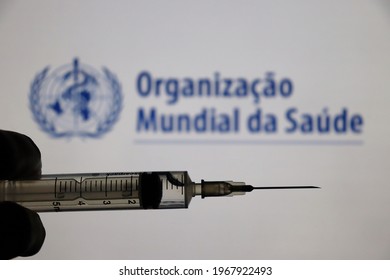 Bahia, Brazil - May 3, 2021: World Health Organization (Organização Mundial Da Saúde, In Portuguese) Logo Displayed On A Screen And Hand Holding A Syringe. Covid-19 Vaccine Concept. 