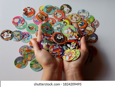 Bahia, Brazil - September 29, 2020. Girl's Hands Holding Collection Of Tazos. Looney Tunes Tazos. 