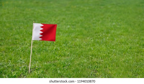 Bahrain Flag. Photo of Bahrain flag on a green grass lawn background. National flag waving outdoors. - Powered by Shutterstock