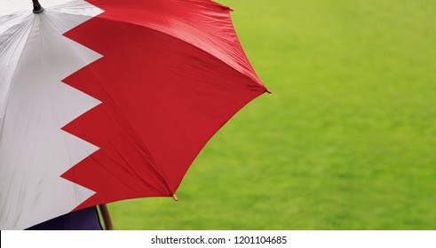 Bahrain Flag Umbrella. Closeup Of Printed Umbrella Over Green Grass Field Background. Landscape, Side View. Rainy Weather/ Climate Change And Global Warming Concept.