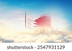 Bahrain flag wavering in beautiful clouds with building skyline. The flag fadding in the clouds. Bahrain national flag for independence day.