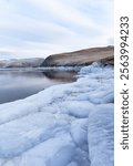 Baikal Lake in December during freeze-up. View of the Olkhon Gate Strait and Olkhon Island in the distance. Icy shore on a frosty day. Scenic landscape. Natural background. Winter travel and outdoors