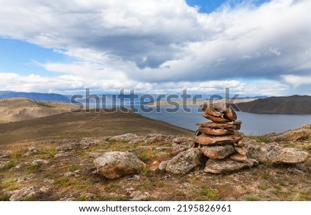 Baikal Lake in early autumn. View from top of Cape Cross to Olkhon Gate Strait, Small Sea and Olkhon Island. Stone pyramid at top of cape built by tourists. Travel and outdoors. Beautiful landscape
