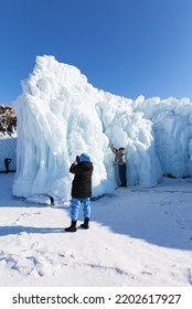 Baikal Lake On Sunny Winter Day. Favorite Pastime Of Tourists Is Photographing Unusual Icy Rocks Of Olkhon Island, Covered With Bizarre Icicles. Unforgettable Ice Travel, Winter Outdoor Recreation