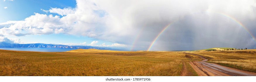 Baikal Lake. Small Sea Strait. Beautiful panoramic view of the steppe part of Olkhon Island with a rainbow over a dirt road to Cape Khoboy. Autumn landscape. Natural background