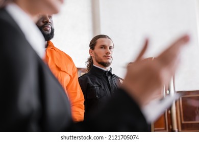 bailiff looking at blurred prosecutor while standing near accused african amrican man in court