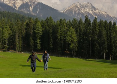 Baisaran Valley, Kashmir, India : March 28, 2019 - Asian Tourists couple enjoying with Running on the lush green Baisaran Valley of Pahalgam which is also called Mini Switzerland for its beauty.