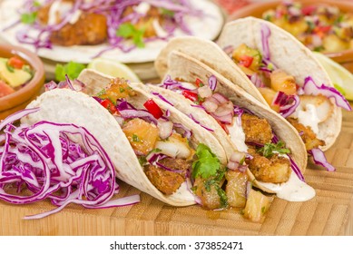 Baja Fish Tacos - Soft shell tacos gefüllt mit frittiertem weißem Fisch, serviert mit rotem Kohl, Ananas Salsa, chunkigem Guacamol und cremiger Baja-Sauce.