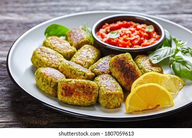 baked broccoli tots on a plate with marinara sauce on a dark wooden table, horizontal view from above - Shutterstock ID 1807059613