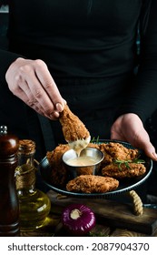 Baked Buffalo Chicken Wings On A Plate In The Hands Of A Chef On A Black Background.