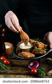 Baked Buffalo Chicken Wings On A Plate In The Hands Of A Chef On A Black Background.