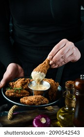 Baked Buffalo Chicken Wings On A Plate In The Hands Of A Chef On A Black Background.