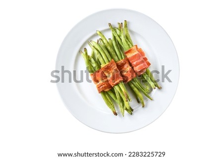 baked bundle of green beans wrapped in a bacon on a white bowl isolated . Green beans rolled in bacon and baked.