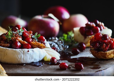 Baked Camembert Brie Cheese With A Cranberry, Honey, Balsamic Vinegar And Nut Relish And Garnished With Thyme. Served With Toasted Bread Slices. Selective Focus With Blurred Background And Foreground.