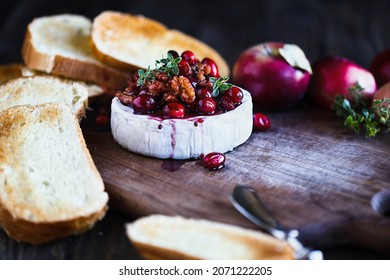 Baked Camembert Brie Cheese With A Cranberry, Honey, Balsamic Vinegar And Nut Relish And Garnished With Thyme. Served With Toasted Bread Slices. Selective Focus With Blurred Background And Foreground.