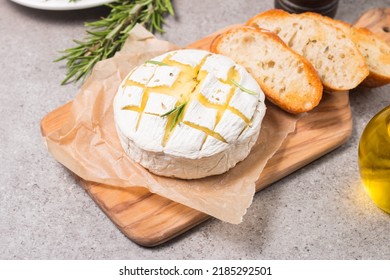 Baked camembert soft cheese. Grilled brie with toasts and rosemary. 