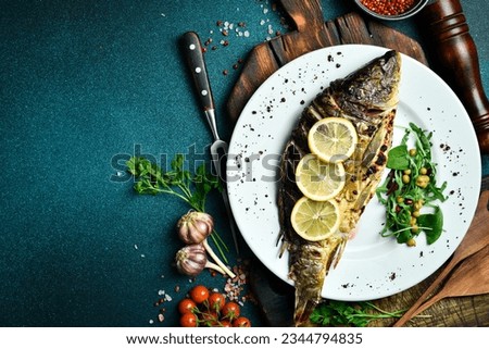Baked carp fish with lemon and herbs. Barbecue menu. Free space for text. Close up.