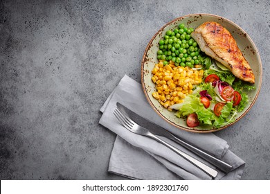 Baked Chicken Breast On Plate With Fresh Salad, Green Peas And Corn, Grey Stone Background, Top View. Healthy Fitness Meal With Chicken Fillet, Balanced In Proteins And Carbs. Overhead, Copy Space