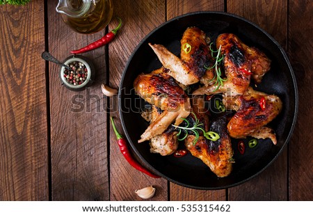 Baked chicken wings in pan on wooden table. Top view