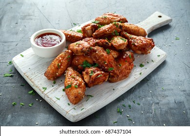 Baked chicken wings with sesame seeds and sweet chili sauce on white wooden board. - Shutterstock ID 687437104