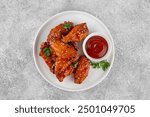 Baked chicken wings in a sweet chili sauce and sesame seeds on a white plate on a concrete background. Top view, copy space