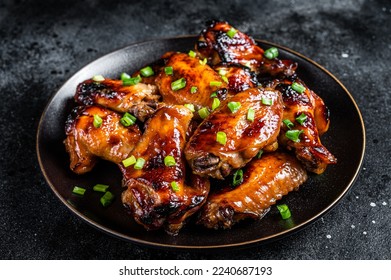 Baked chicken wings with sweet chili sauce in a plate. Black background. Top view. - Powered by Shutterstock