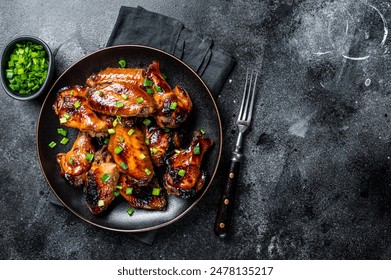 Baked chicken wings with sweet chili sauce in a plate. Black background. Top view. Copy space. - Powered by Shutterstock