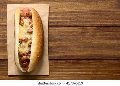 Baked Chili Hot Dog, Photographed Overhead On Dark Wood With Natural Light