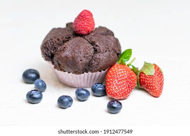 Baked chocolate muffin with juicy berries, strawberries, blueberries, raspberries