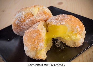 baked custard Doughnuts, homemade donut with filled custard and icing sugar topped on black dish, selective focus
