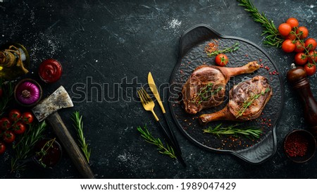 Baked duck thigh with spices and rosemary. Barbecue meat. Top view. Flat lay top view on black stone cutting table.