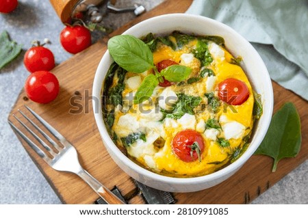 Baked egg omelette with spinach, cherry tomato and feta cheese on a stone surface. Healthy vegetarian breakfast. 