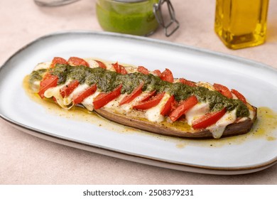 Baked eggplant with mozzarella cheese, tomatoes and pesto sauce. Traditional homemade seasonal dish. Grilled stuffed eggplant. Hearty summer dish. Selective focus, close-up. - Powered by Shutterstock