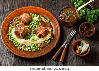 baked faggots served with creamy mashed potatoes, green peas and rich, thick onion gravy on a clay plate, english cuisine