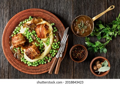 baked faggots served with creamy mashed potatoes, green peas and rich, thick onion gravy on a clay plate, british cuisine, flat lay