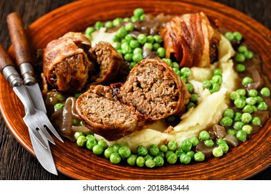 baked faggots served with creamy mashed potatoes, green peas and rich, thick onion gravy on a clay plate, british cuisine, close-up