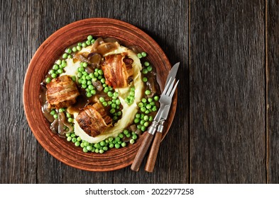 baked faggots served with creamy mashed potatoes, green peas and rich, thick onion gravy on a clay plate, british cuisine, flat lay, free space