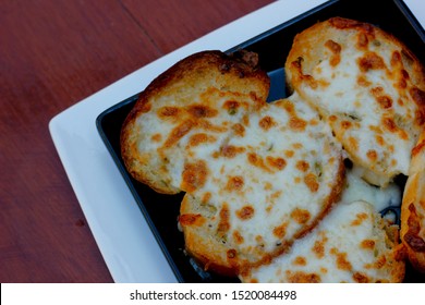 Baked Garlic Bread With Cheese Homemade At Home, Placed On A Plate On An Old Wooden Cooking Table, View From Above