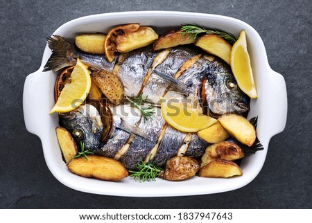 Baked gilt-head bream (dorade) fish with potatoes, herbs and spices.