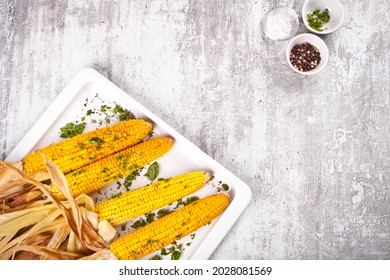 Baked grilled sweet corn cobs with herbs, butter on the white tray