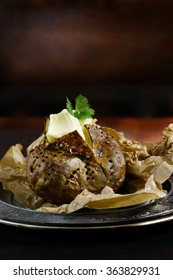 Baked Jacket Potato With A Wedge Of Butter And Garnish Against A Rustic Background. Generous Accommodation For Copy Space. The Perfect Image For Your Lunch Menu Cover Design.